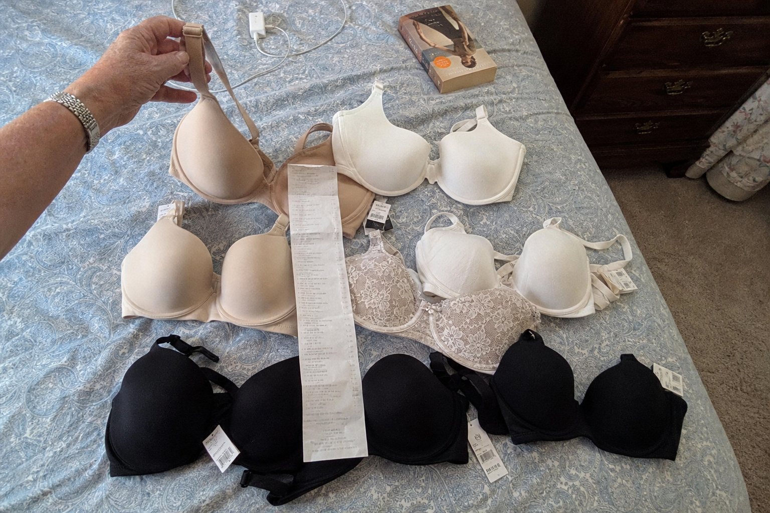 Nine bras laid out on a bed, some with price tags