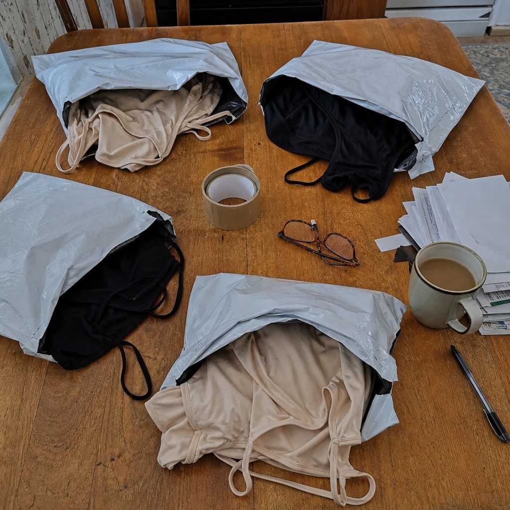 Four return mailers with thin camisoles on a kitchen table